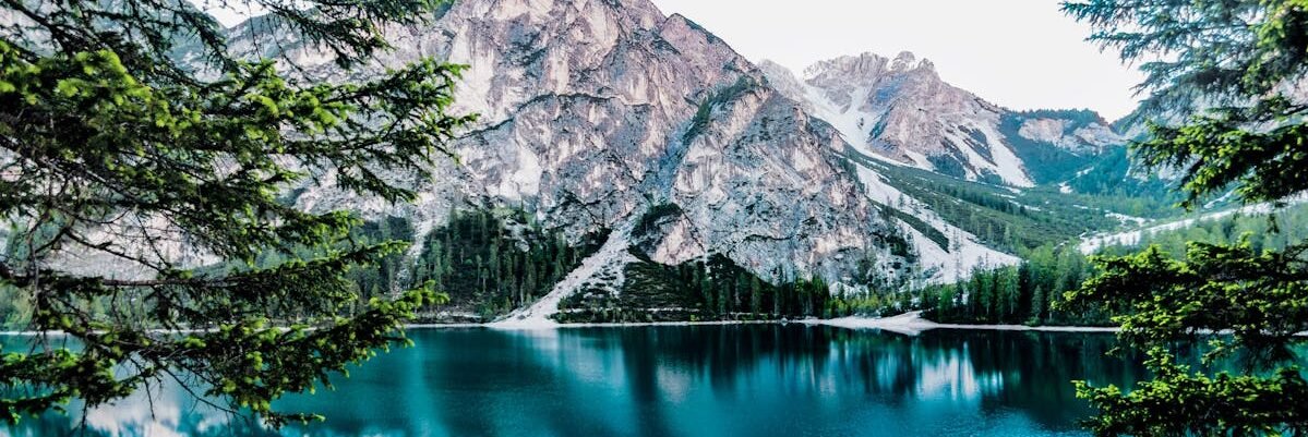 Serene mountain lake with stunning reflections in Braies, Italy, surrounded by trees.