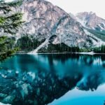 Serene mountain lake with stunning reflections in Braies, Italy, surrounded by trees.